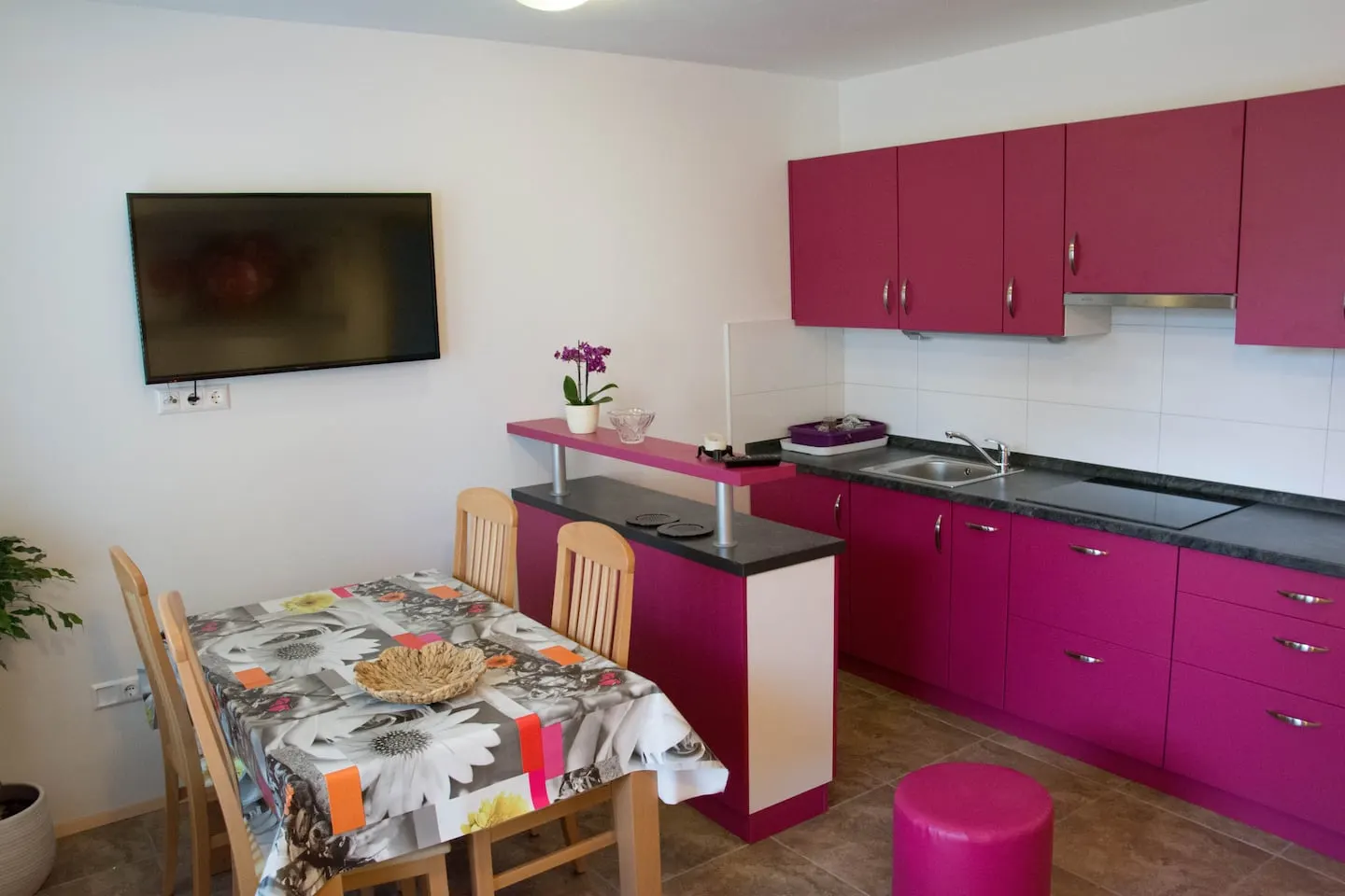 Roza apartma: kuhinja z roza omaricami in jedilna miza