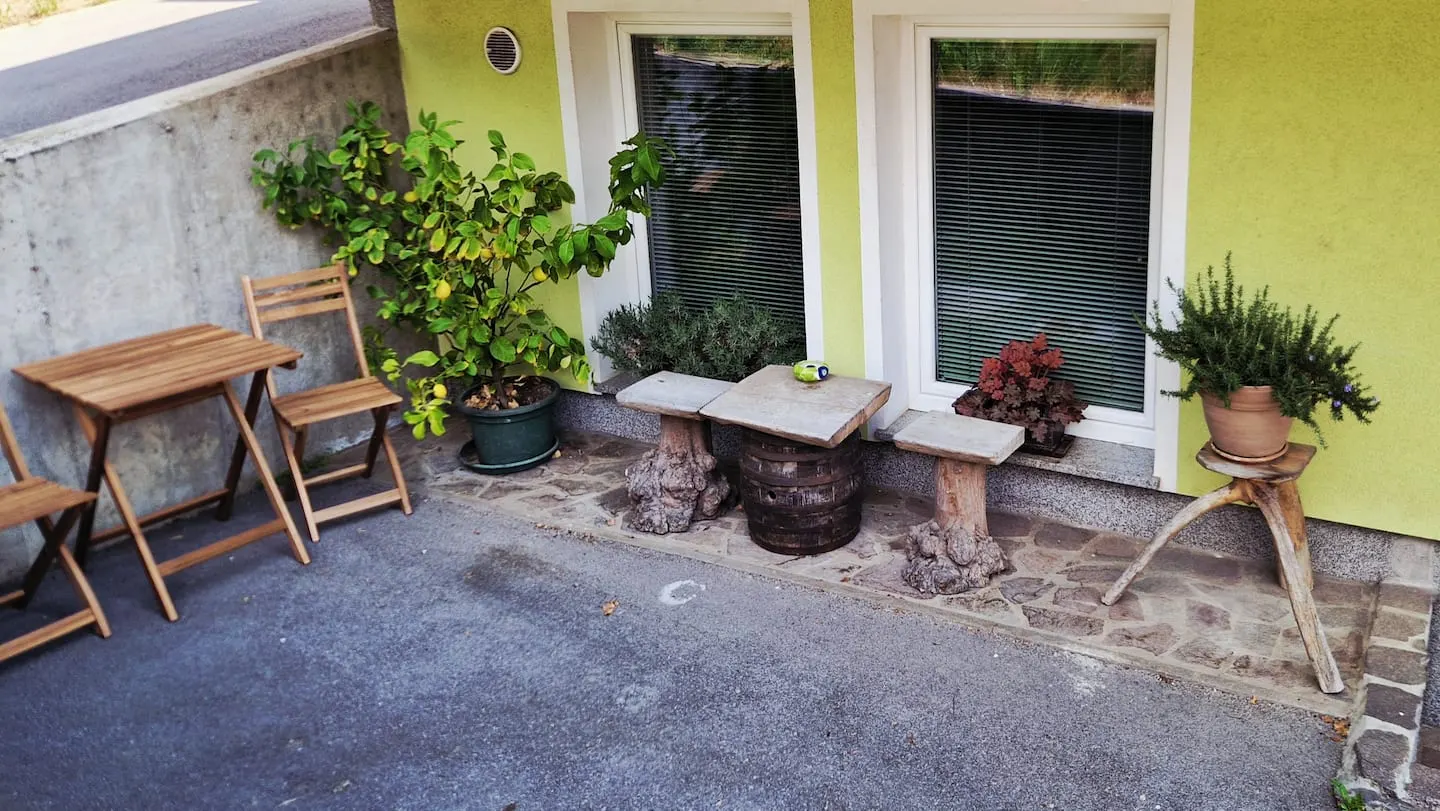 Lesena mizica in stoli pred roza apartmajem, med lončnicami