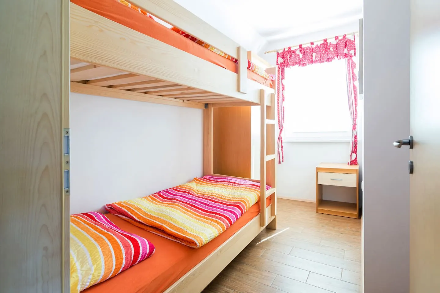 Spalnica rdečega apartmaja s pogradom in črtasto posteljnino
