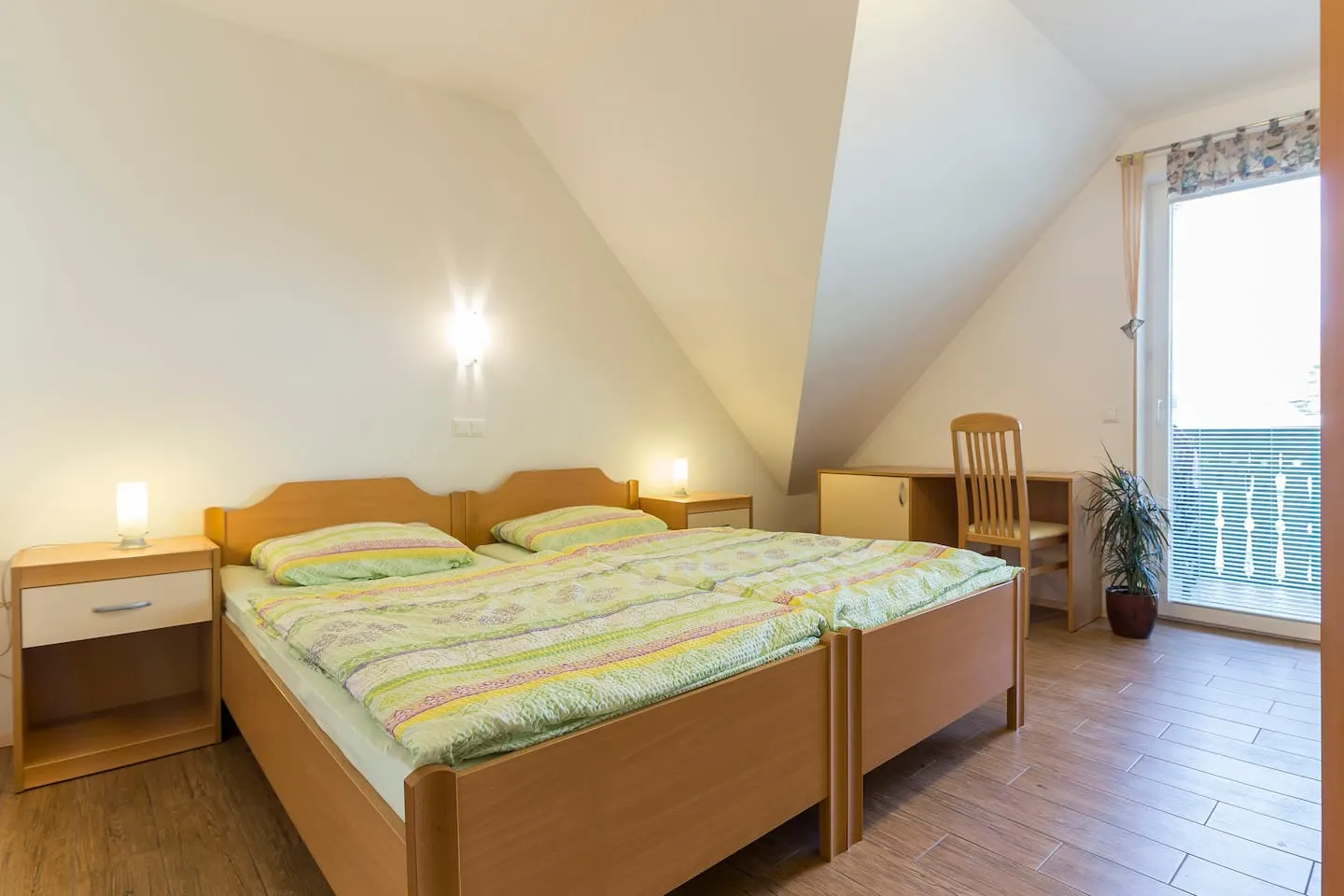 Spalnica s staknjenima posteljama in vrati na balkon